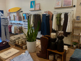 Clothing store interior with racks of clothes, boots, and decor items.