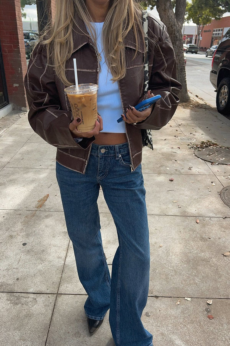 Person holding a drink and phone on a sidewalk